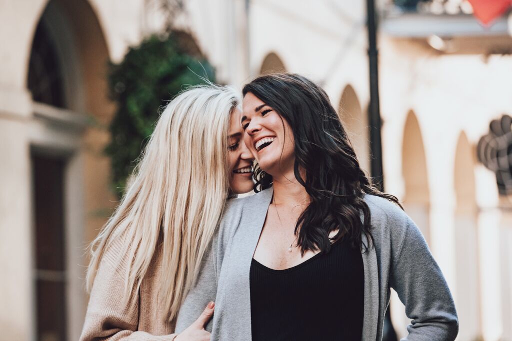 Two women laugh together during their engagement portrait in New Orleans.