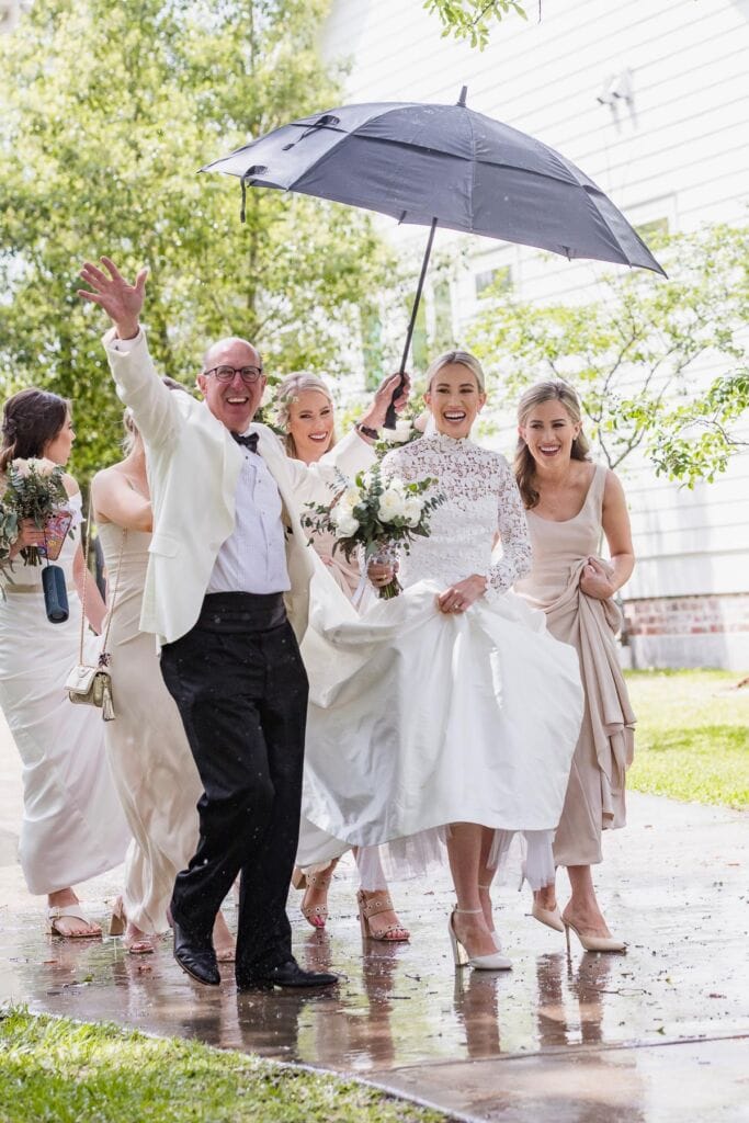 Wedding celebration in New Orleans with joyful bride, groom, and friends under an umbrella.