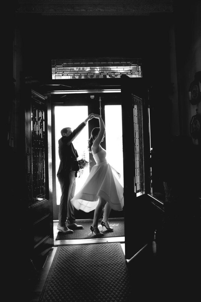 Elegant bride twirling with her partner at the doorway.