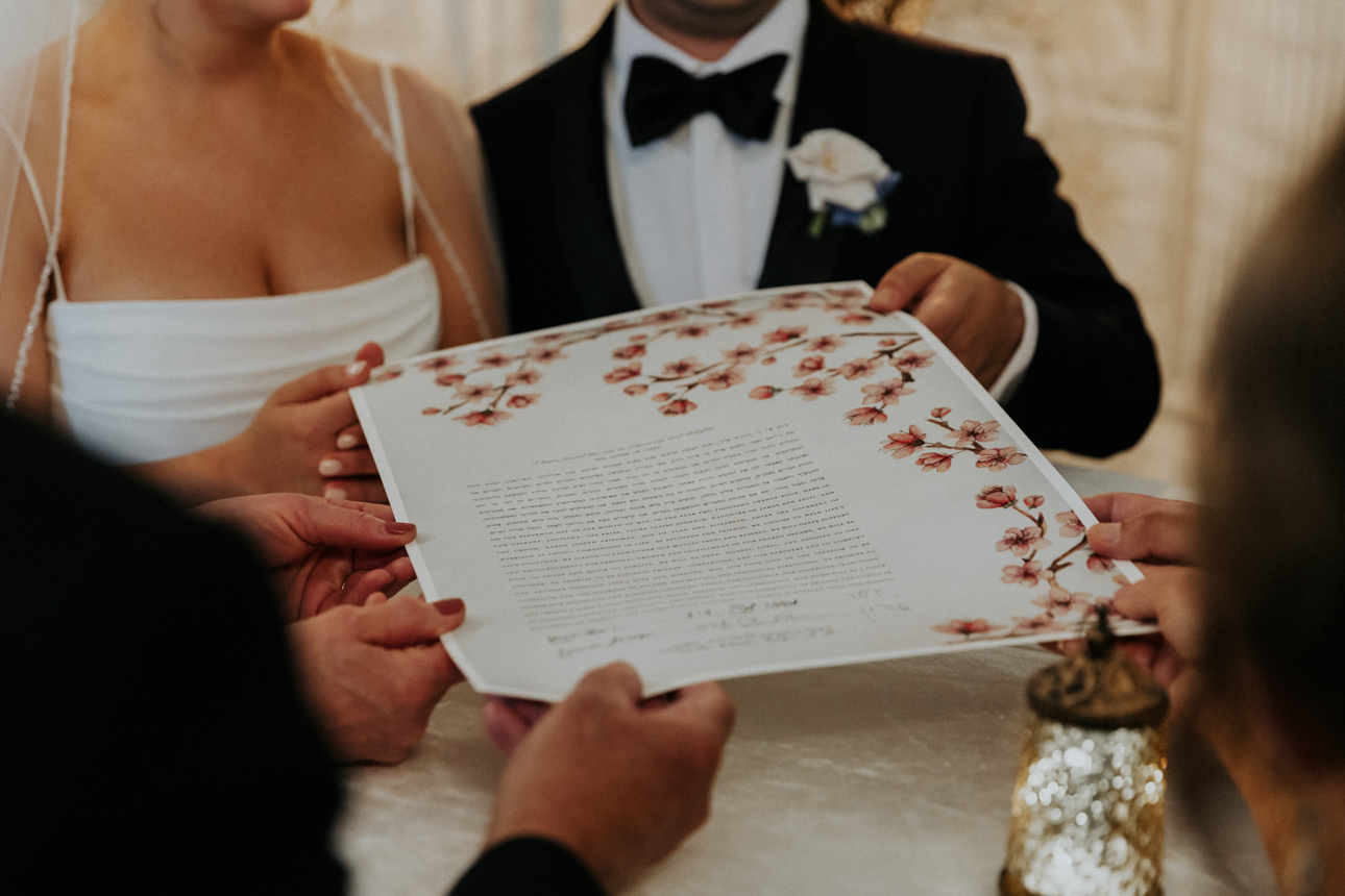 A bride and groom and their parents hold the Ketubah.