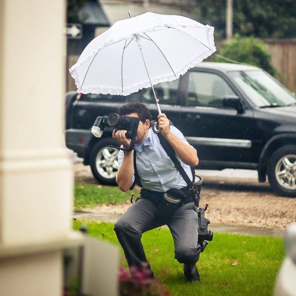 Matthew Foster taking photos holding a camera and a white secondline umbrella.