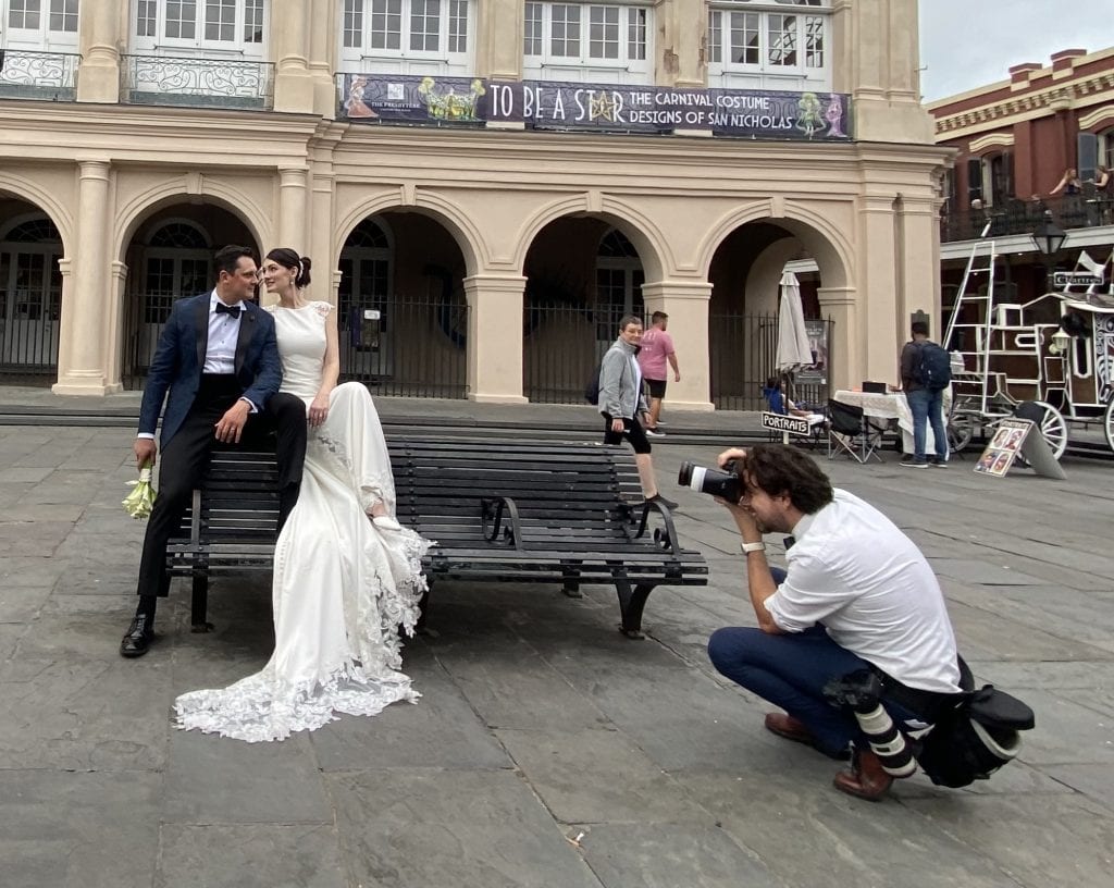 Matthew Foster photographing a bride and group sitting on a bench in Jackson Square New Orleans.