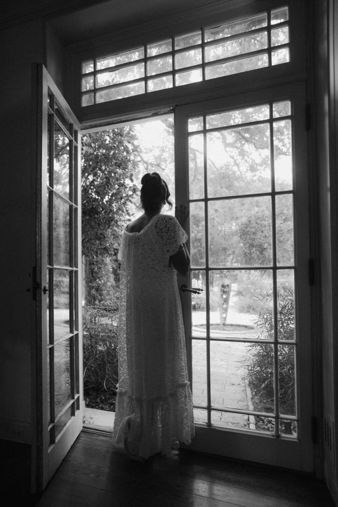 Bride looking outside the window in a romantic wedding image.