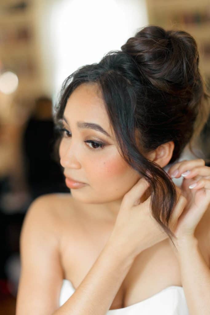 Beautiful bride with styled hair and professional makeup in a candid moment.