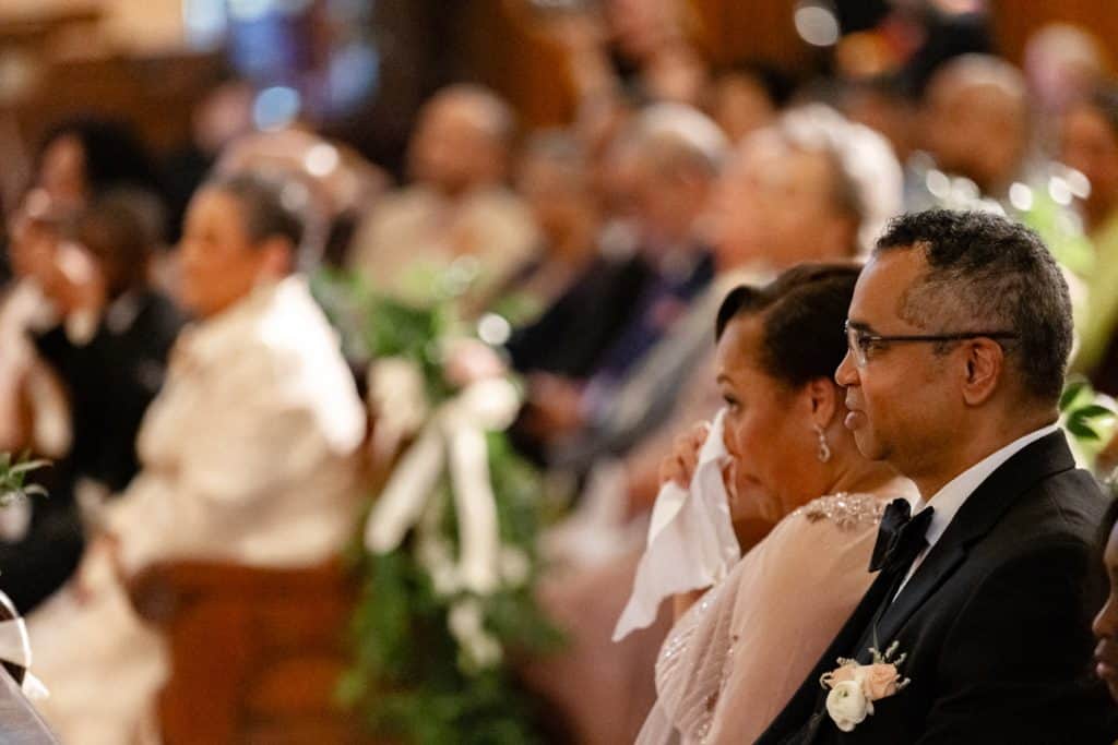 A diverse group of wedding attendees attentively listens during a New Orleans wedding ceremony, showing emotional engagement.