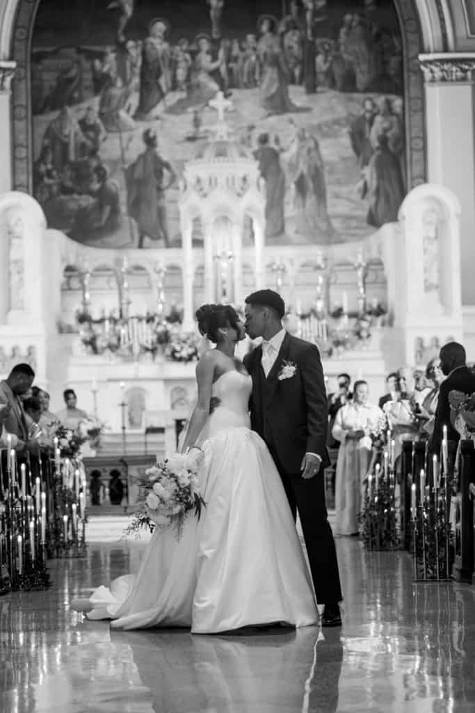 Romantic bride and groom sharing first kiss at wedding ceremony in historic church.
