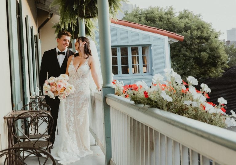 Wedding couple on the balcony at The Marche in New Orleans with flowers and charming architecture.