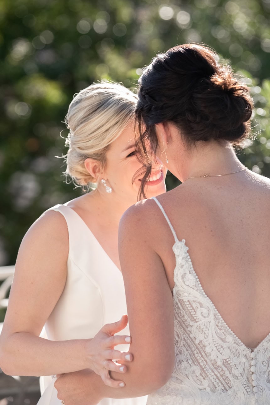 Two brides sharing a joyful moment outdoors during a wedding in New Orleans.