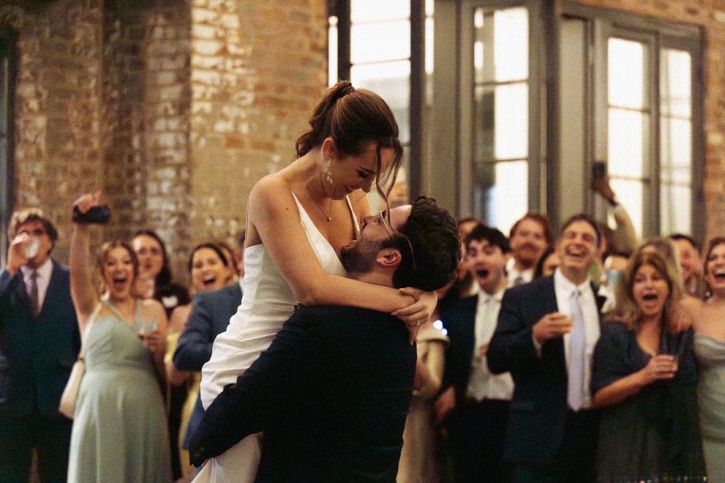 Happy bride and groom sharing a dance surrounded by friends and family in a lively wedding celebration at Margaret Place in New Orleans,