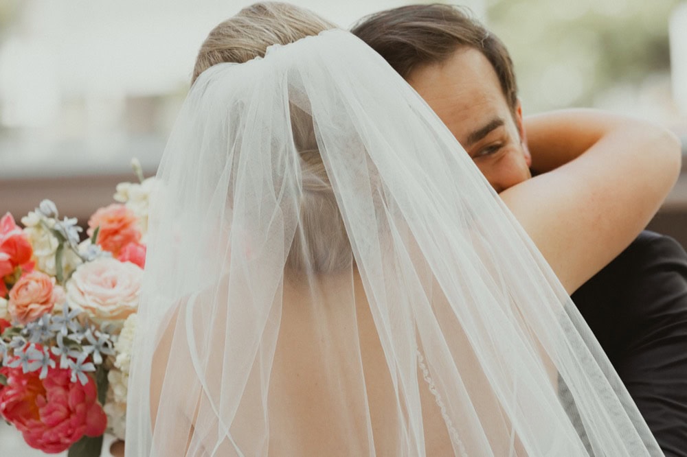 Bride and groom sharing a tender moment, with the bride's veil covering her face.