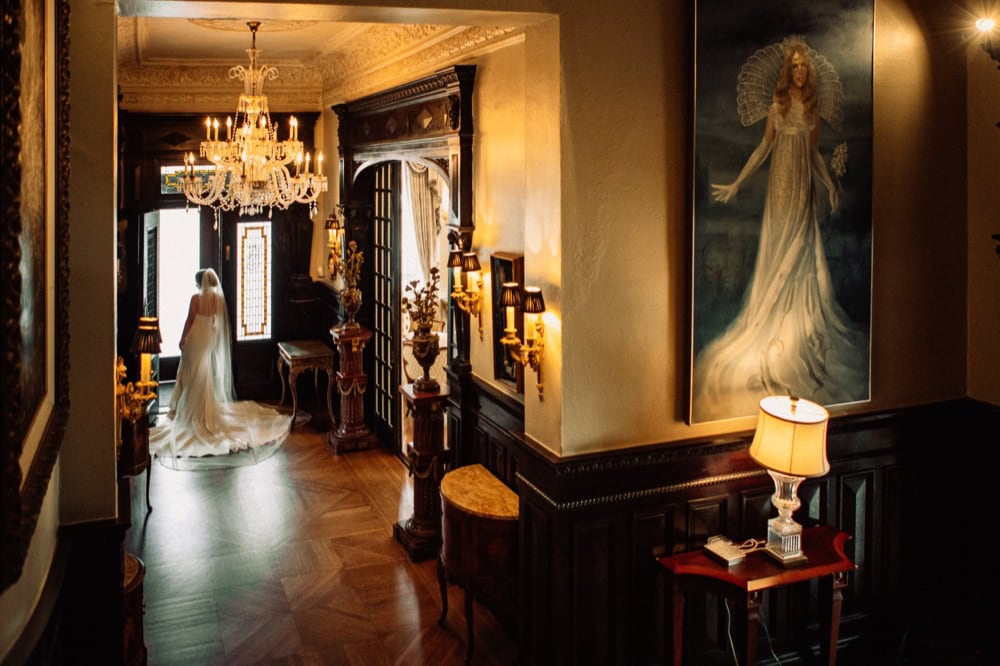 Elegant interior of the Elms Mansion featuring a bride in a gown by the window.