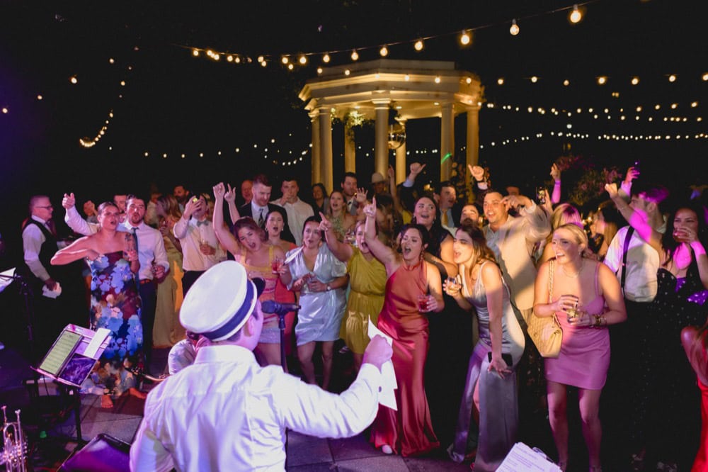 Vibrant wedding reception in New Orleans with guests dancing under string lights at night.