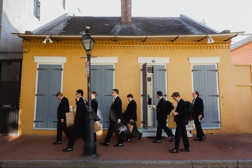 Groomsmen walking outside a historic building in New Orleans.