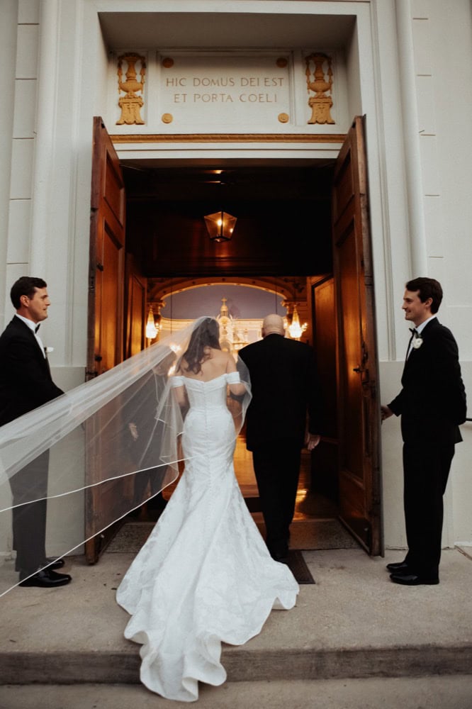 Bride and groom entering church with attendants holding the door open.
