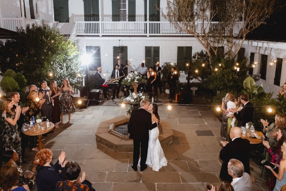Wedding dance at night in a courtyard with guests, string lights, and live band.