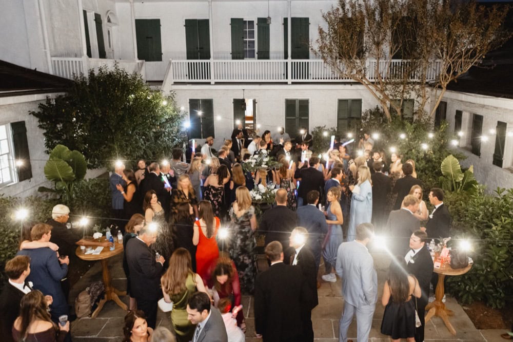 Elegant wedding reception in a charming courtyard with guests dancing and mingling.