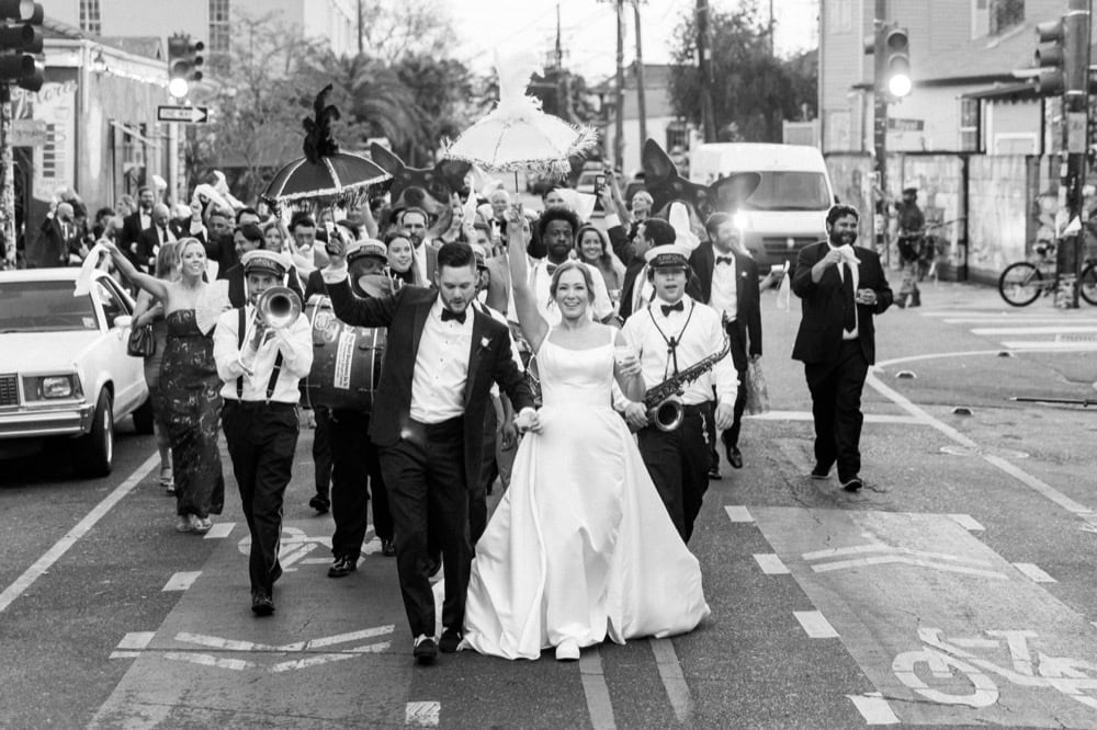 Wedding procession in New Orleans with musicians and guests celebrating.