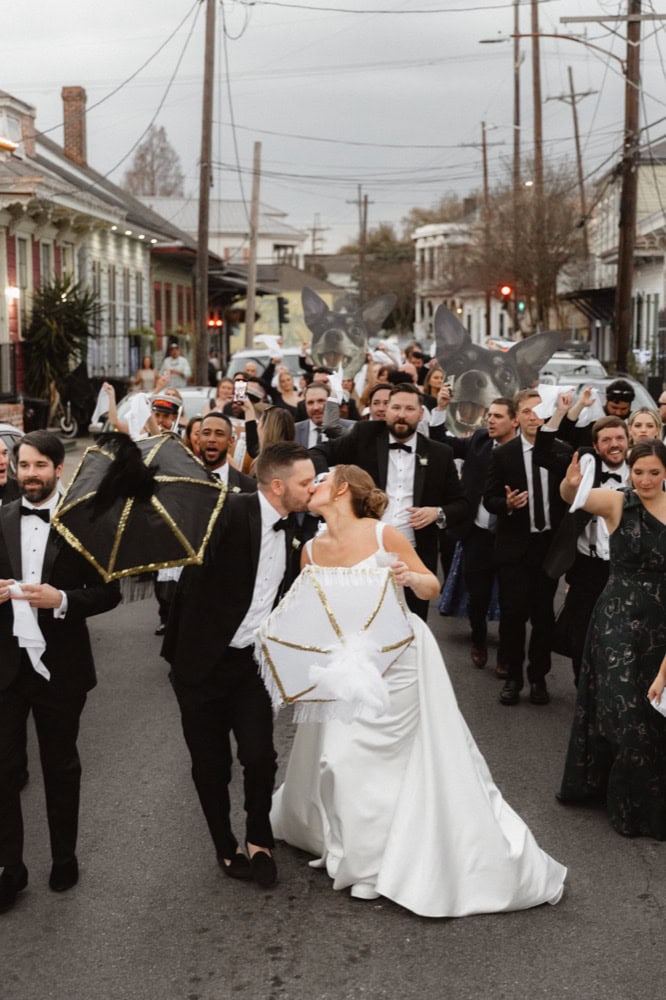 Joyful wedding procession in New Orleans with bride and groom surrounded by friends and family.