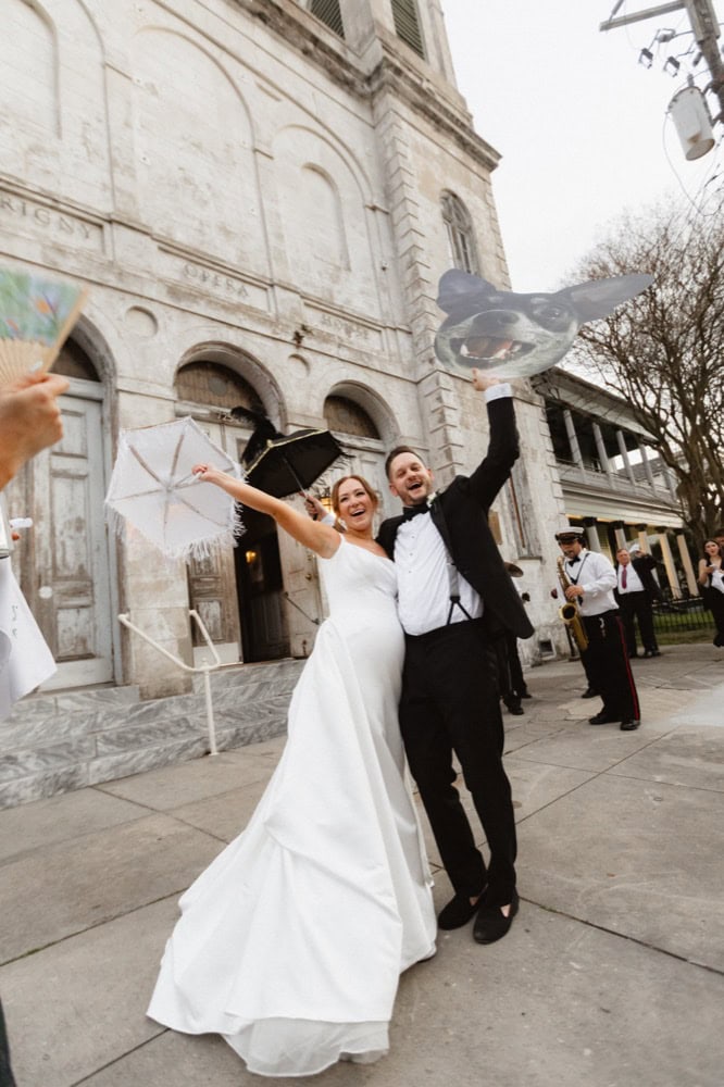 Happy bride and groom celebrating outside a historic New Orleans building, the Marigny Opera House for their wedding.