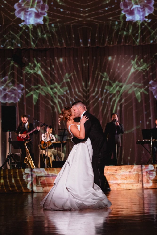 Wedding dance at New Orleans venue with live band and colorful lighting.