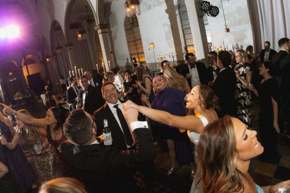 Wedding celebration at a grand venue with dancing and joyful guests.