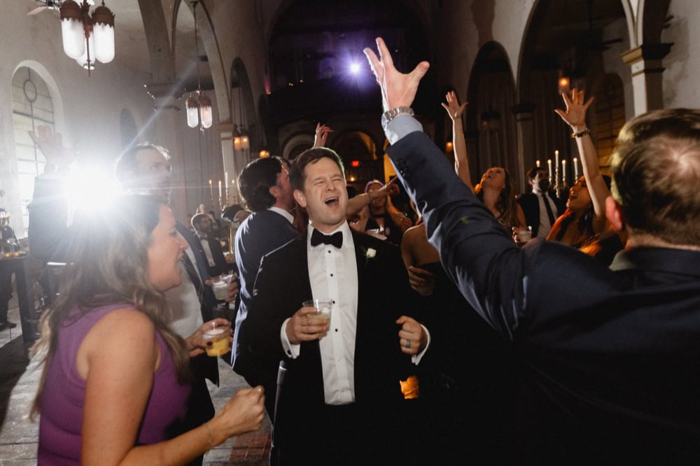 Celebration at a wedding reception with guests dancing and enjoying drinks in a historic New Orleans.