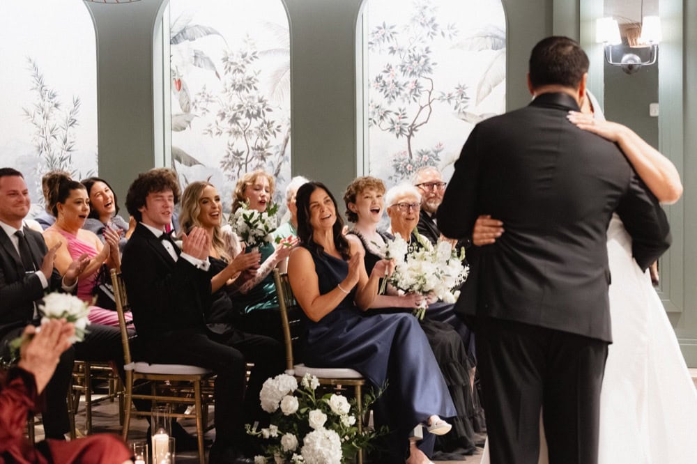 Bride and groom kiss at their wedding at the Virgin Hotel in New Orleans while their guests cheer.