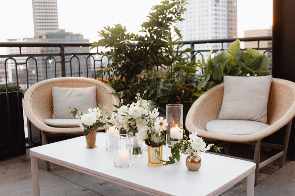 White flowers in gold vases adorn a table on the balcony of the Virgin Hotel in New Orleans for a wedding reception.