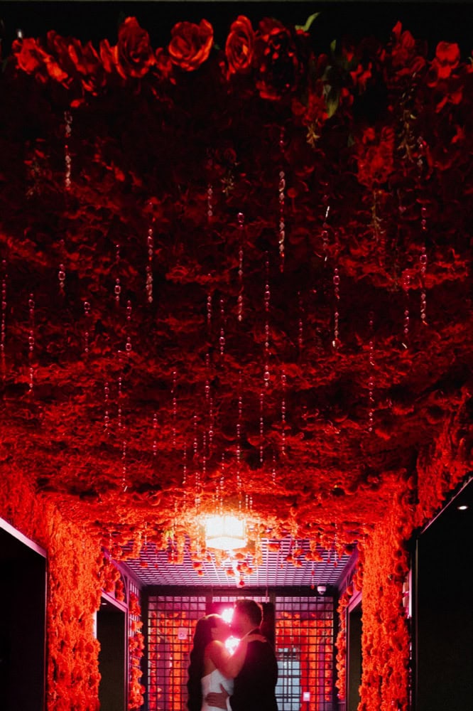 A bride and groom kiss in a rose filled hallway at the Virgin Hotel in New Orleans on their wedding day.