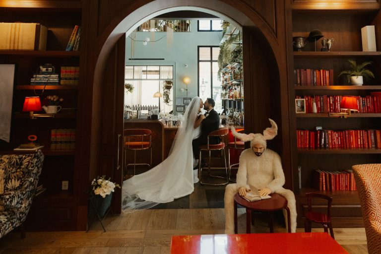 Bride and groom sharing a romantic moment at the bar of the Virgin Hotels New Orleans, framed by a wooden arch.