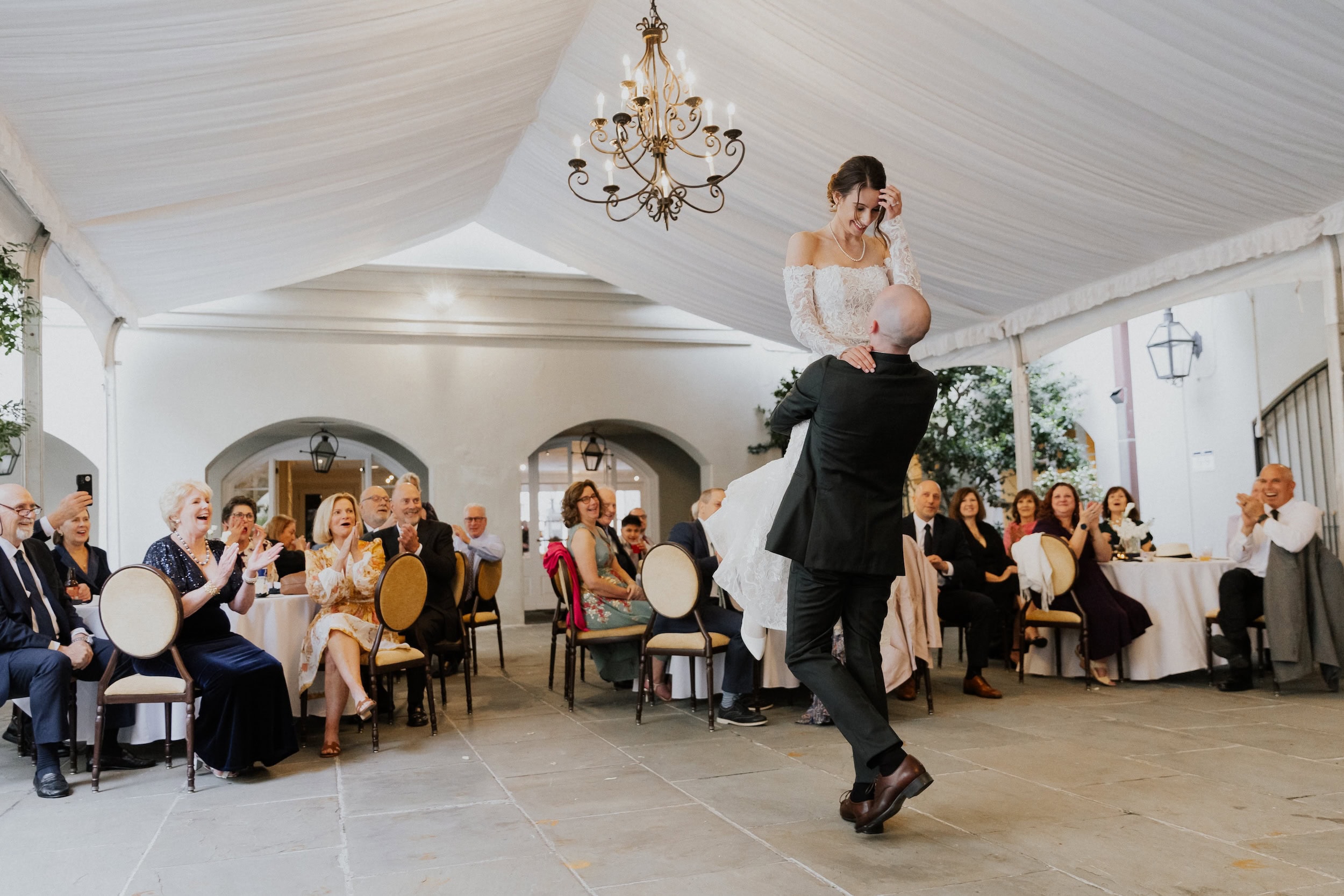 Wedding dance under a white tent with guests enjoying the celebration and elegant decor.
