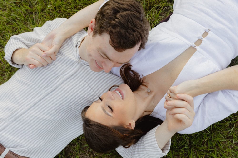 Couple lying on grass during engagement photoshoot in New Orleans.