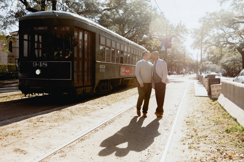 Two men walking along a streetcar track in New Orleans at sunset.