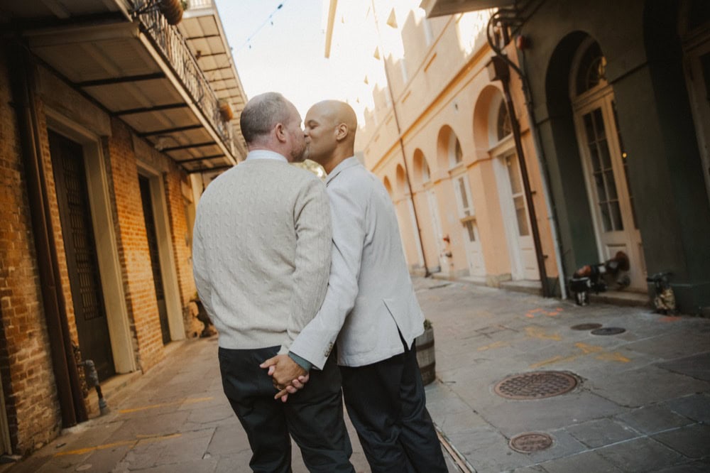 LGBTQ+ couple sharing a kiss in a historic New Orleans street.