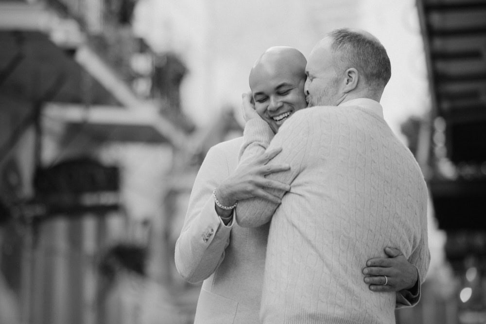 Two men embracing in New Orleans French Quarter during their engagment photoshoot.