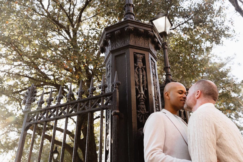 Couple sharing intimate moment near historic iron gate in New Orleans.