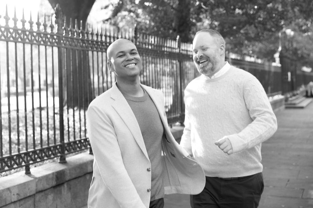 Two men smiling and walking outdoors in New Orleans, candid moment.