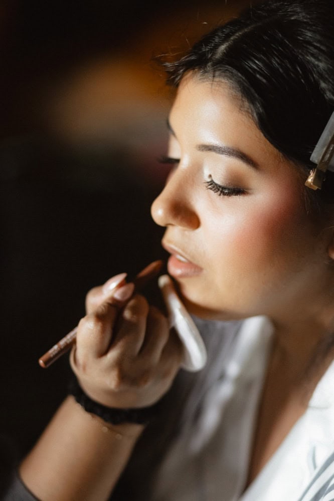 Makeup artist applying makeup to bride with focused expression.