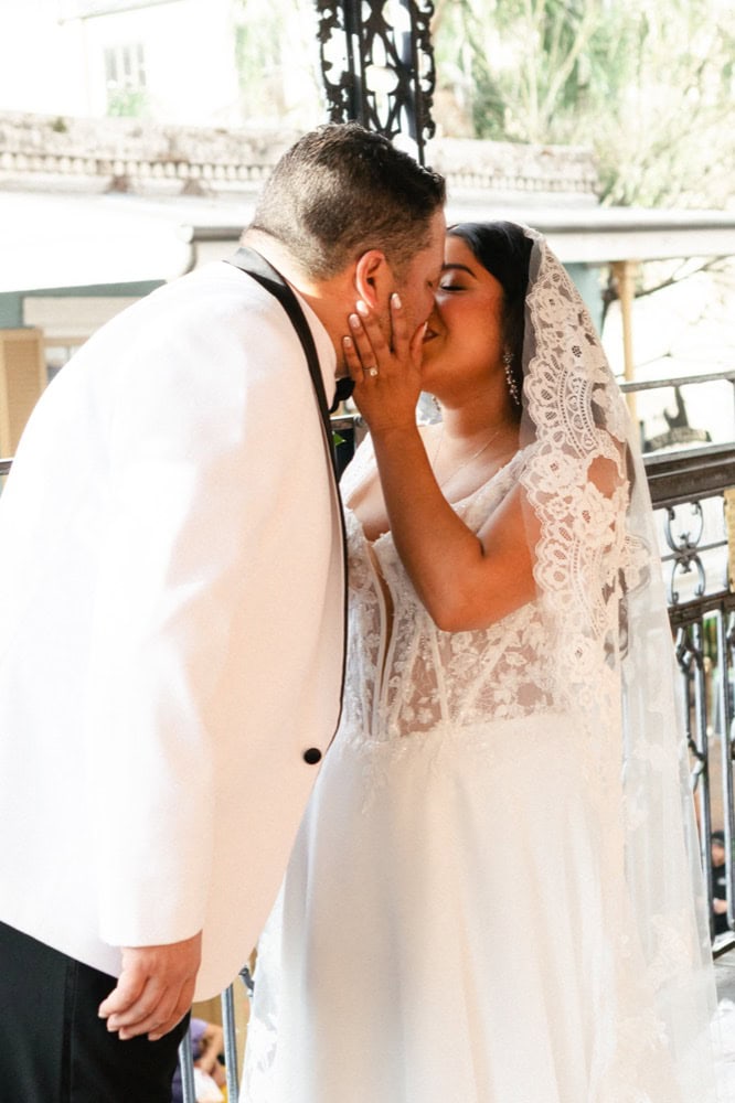 Romantic wedding kiss between bride and groom in New Orleans setting.