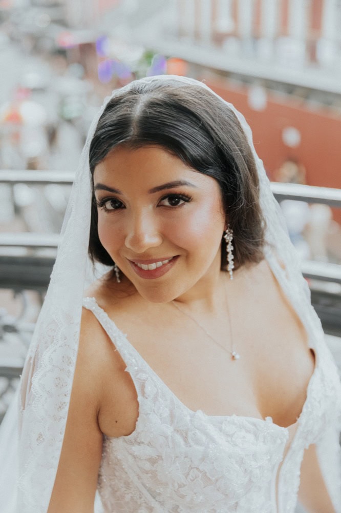 Beautiful bride in wedding dress with veil smiling outdoors in New Orleans.
