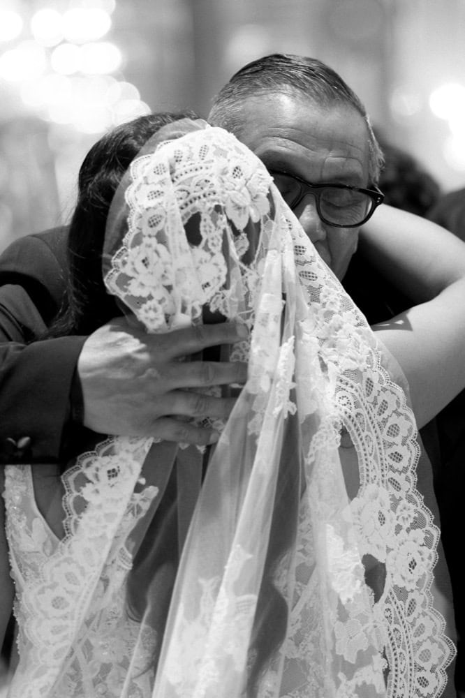 Wedding couple hugging, bride with lace veil and groom in glasses, celebrating love in New Orleans.