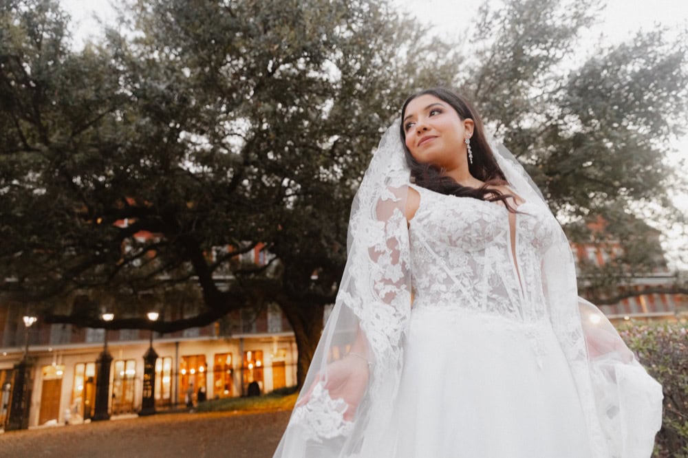 Bride in a white lace wedding dress with veil outdoors in New Orleans.