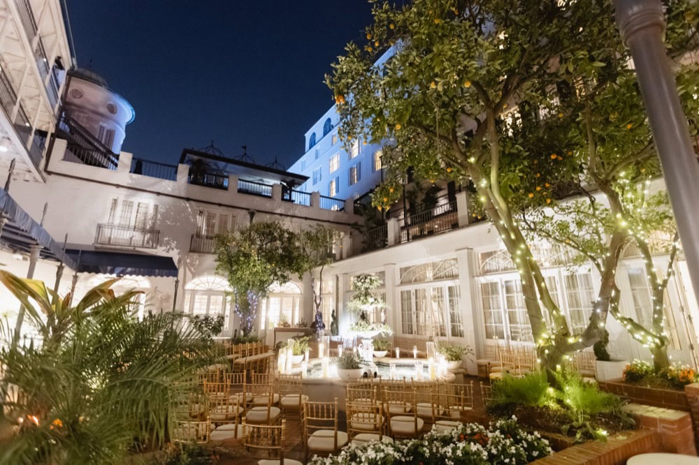 Elegant New Orleans courtyard wedding venue illuminated with string lights and lush greenery at nigh.