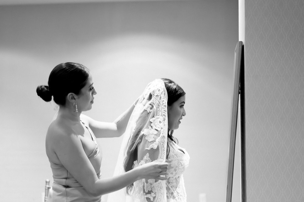 Two women preparing a bride for her wedding in New Orleans, capturing a special moment.