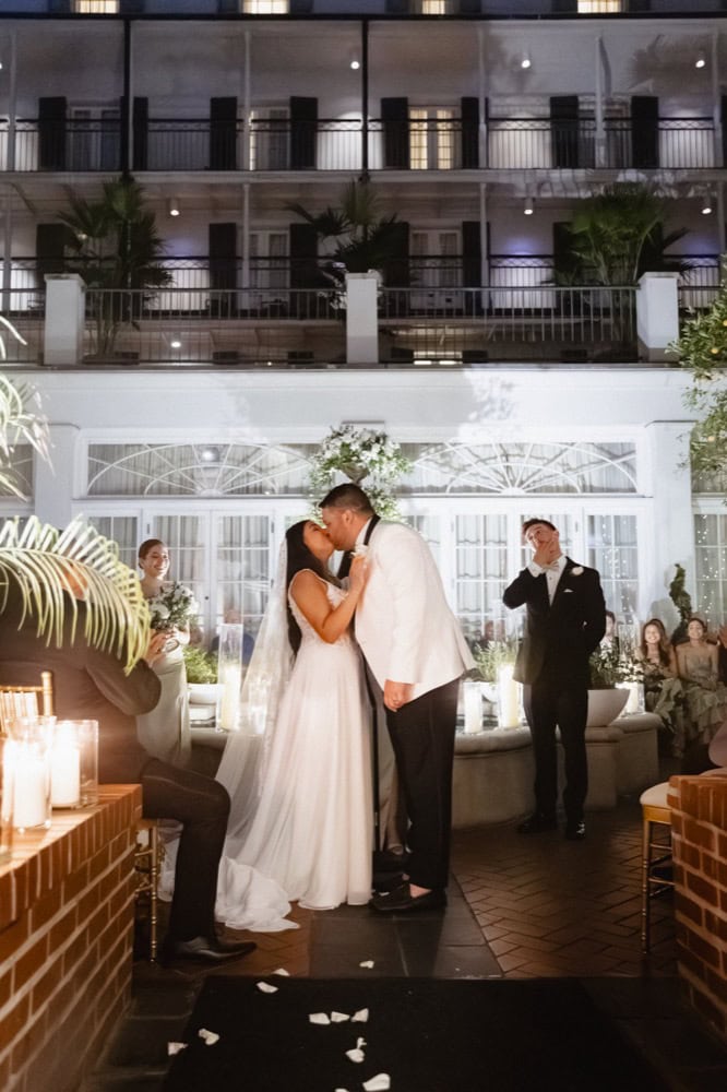 Elegant couple sharing a kiss at a wedding reception in New Orleans.