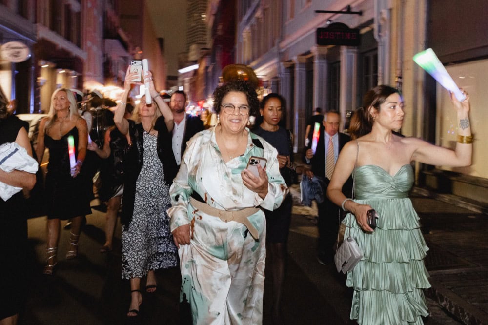 Group of people enjoying nightlife in New Orleans, some holding glow sticks and taking photos.