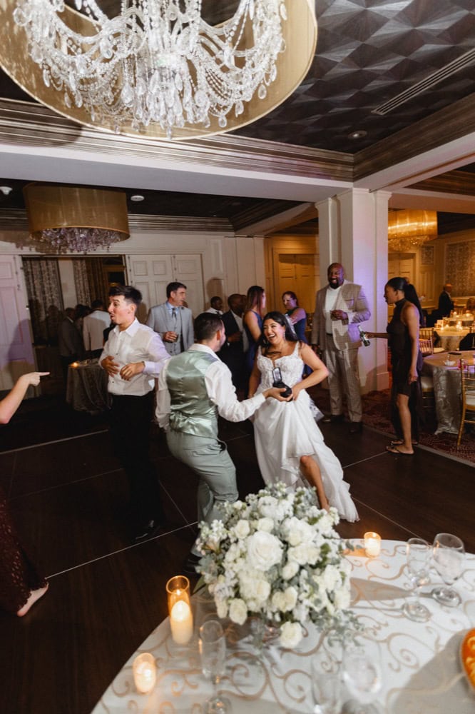Wedding reception dance floor with happy couple and friends celebrating.