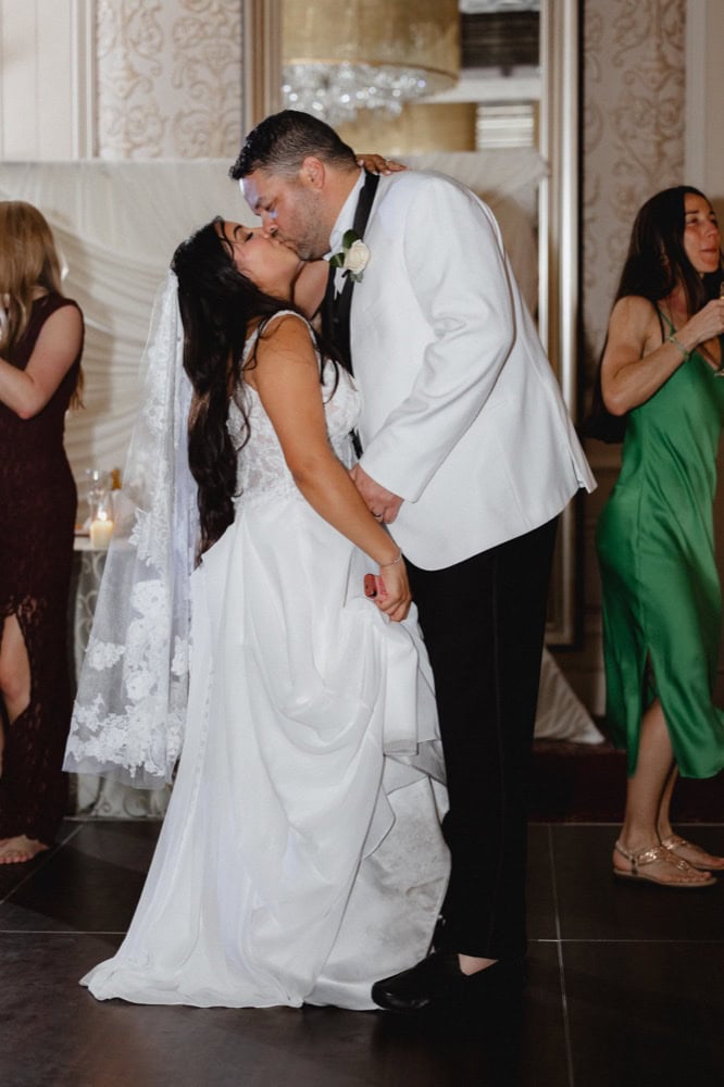 Romantic wedding kiss between bride and groom at New Orleans celebration.