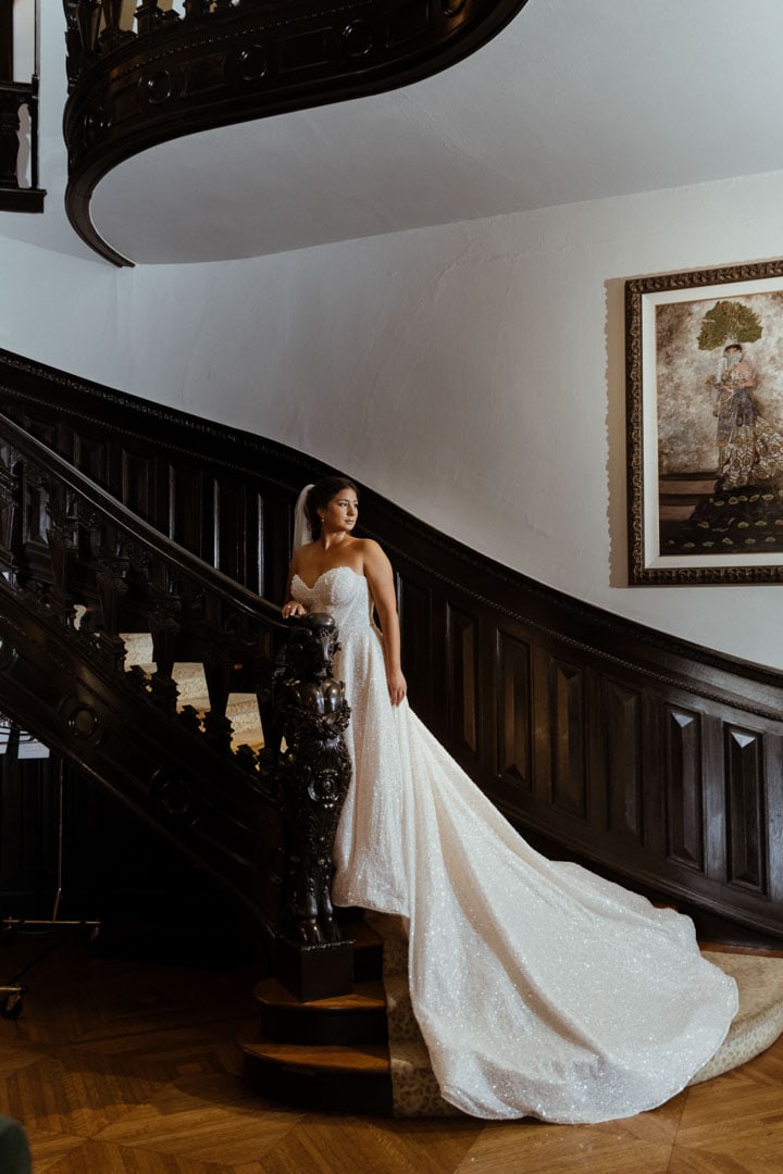 Bride in wedding gown on grand staircase in historic New Orleans home.