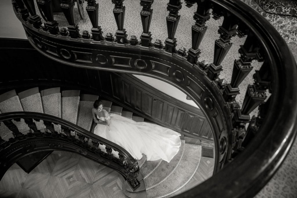 Bride on grand staircase during wedding at historic New Orleans mansion.